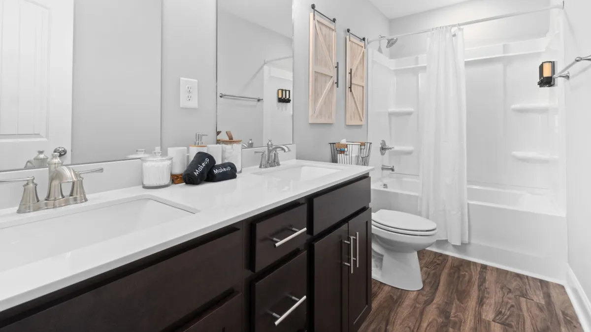 A luxurious bathroom with a double sink vanity, a mirrored wall, decorative wooden shutters, and a separate bathtub and shower area. The space is serene and well-appointed, designed for relaxation and personal care.