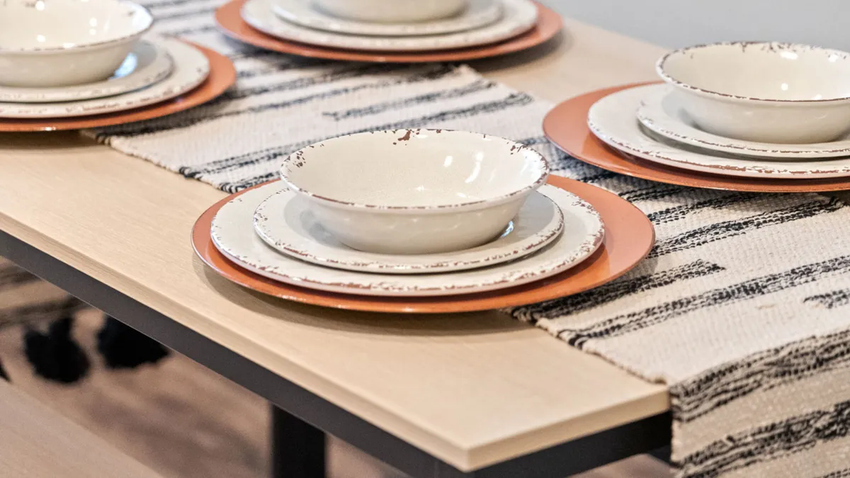 A warmly lit dining area with an inviting table setting, featuring decorative bowls and a tasteful table runner. The space is designed for shared meals, with ample seating that encourages family gatherings and togetherness.
